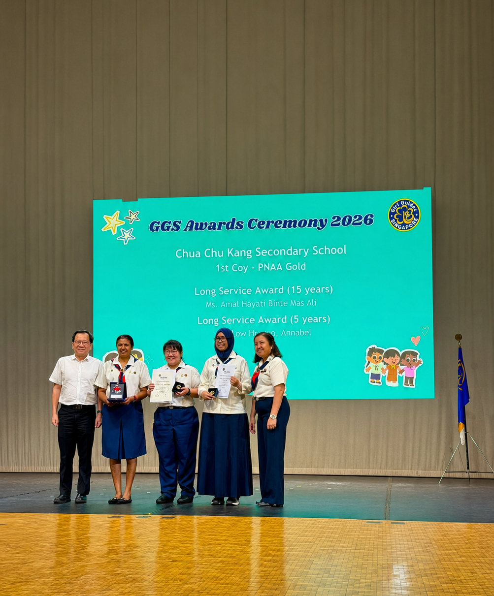 Four women in Girl Guides uniforms and a man in a white shirt pose on stage with awards.